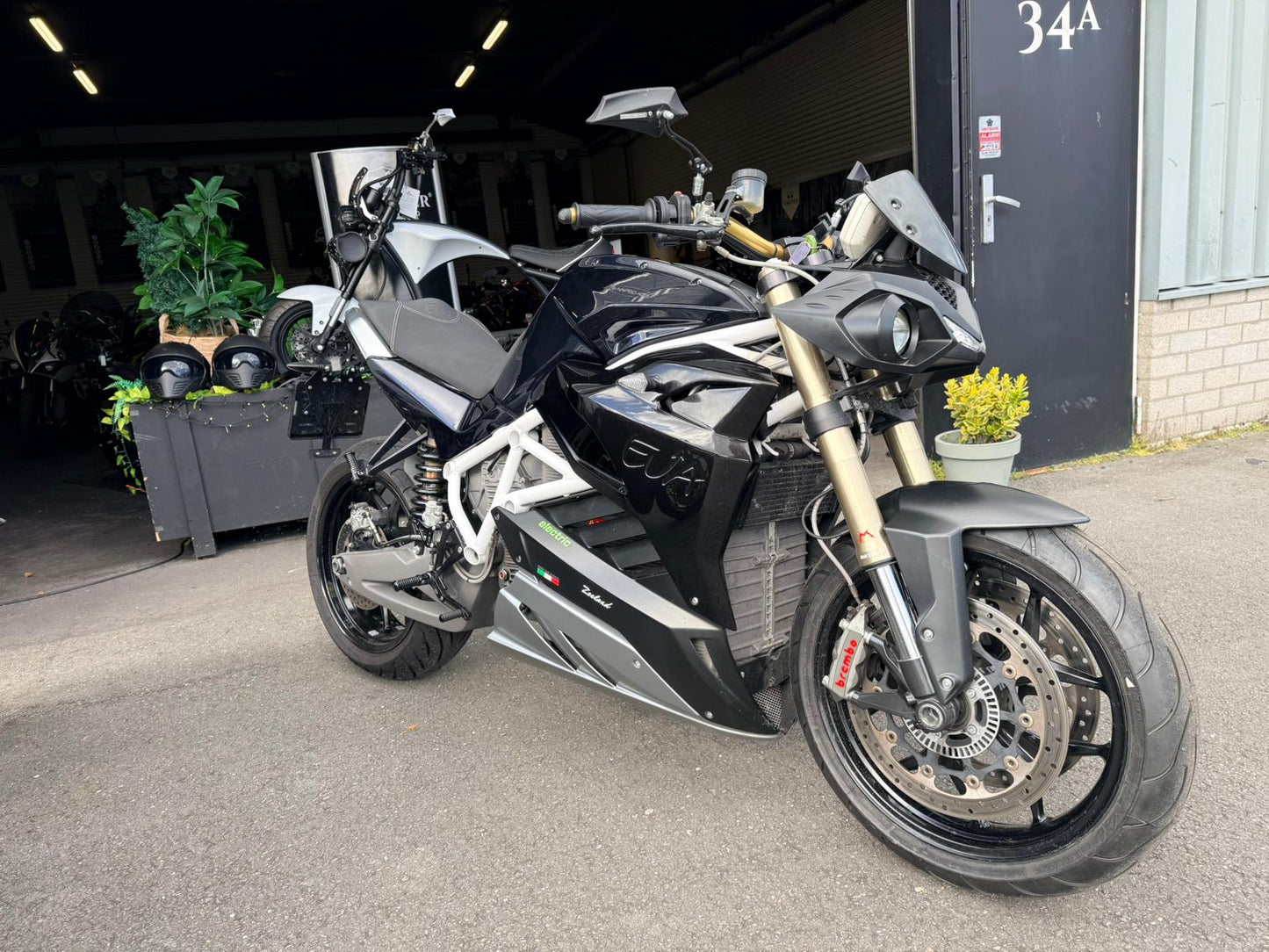 Zwarte Energica EVA R elektrische motorfiets geparkeerd voor een garageingang