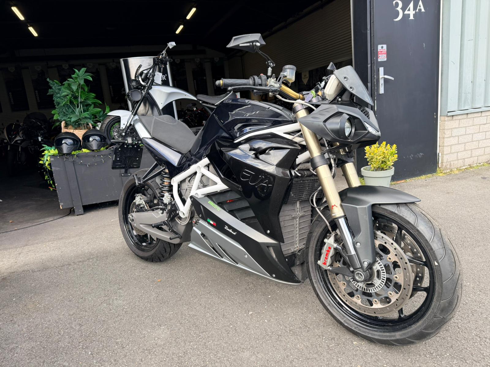 Zwarte Energica EVA R elektrische motorfiets geparkeerd voor een garageingang