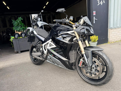 Zwarte Energica EVA R elektrische motorfiets geparkeerd voor een garageingang