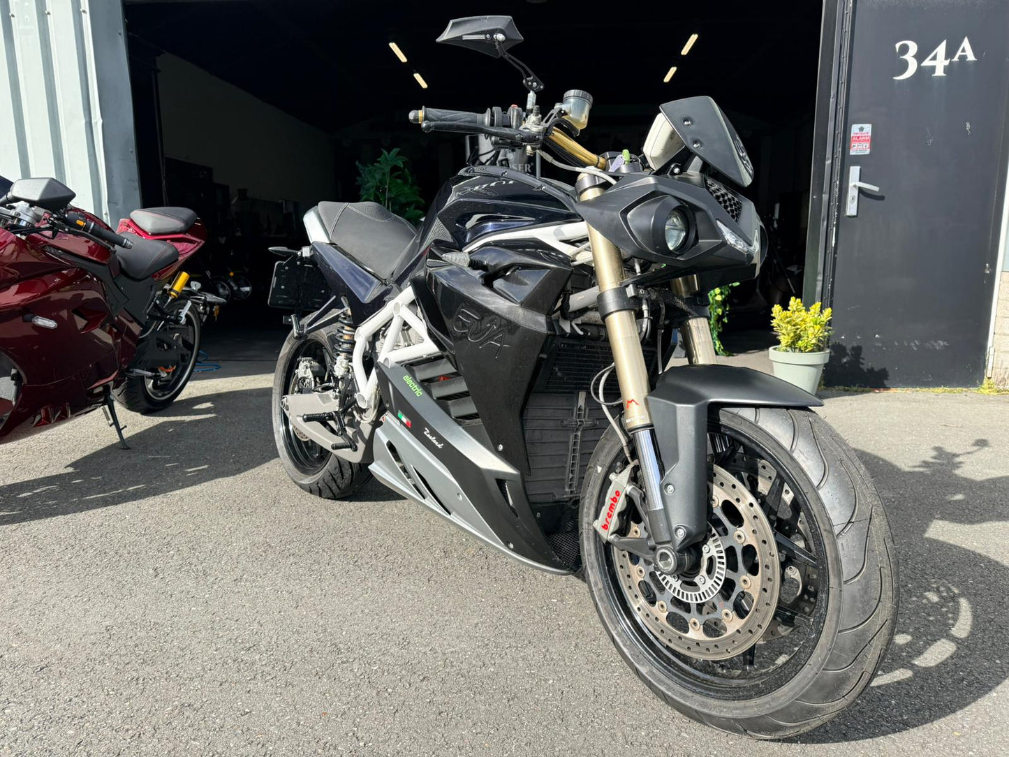 Zwarte Energica EVA R elektrische motorfiets geparkeerd voor een garage