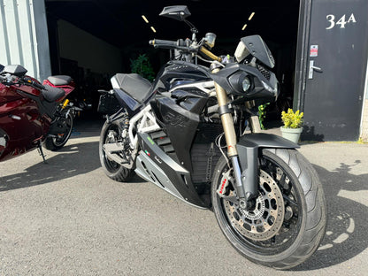 Zwarte Energica EVA R elektrische motorfiets geparkeerd voor een garage