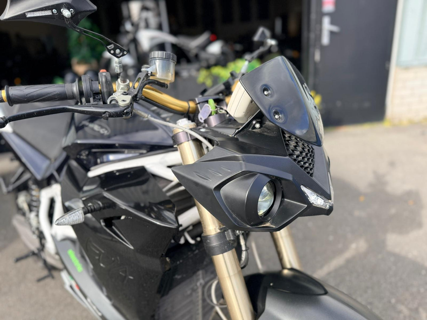 Zwarte Energica EVA R elektrische motorfiets, close-up van het stuur en koplamp