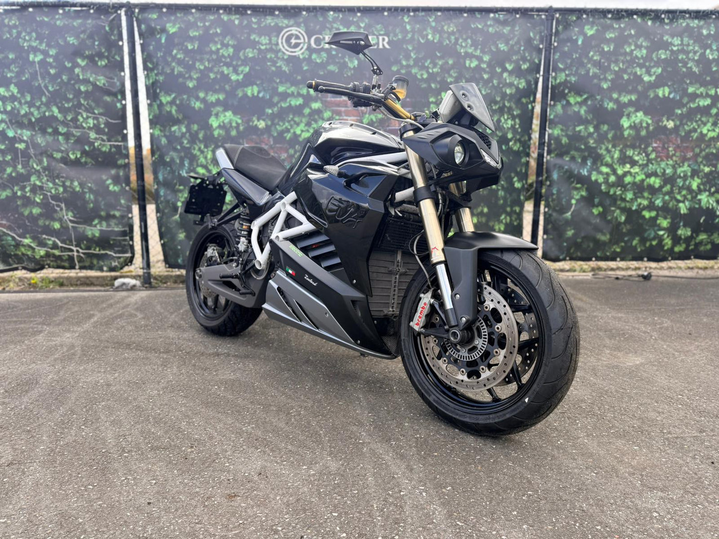 Zwarte Energica EVA R elektrische motorfiets op asfalt voor groene achtergrond