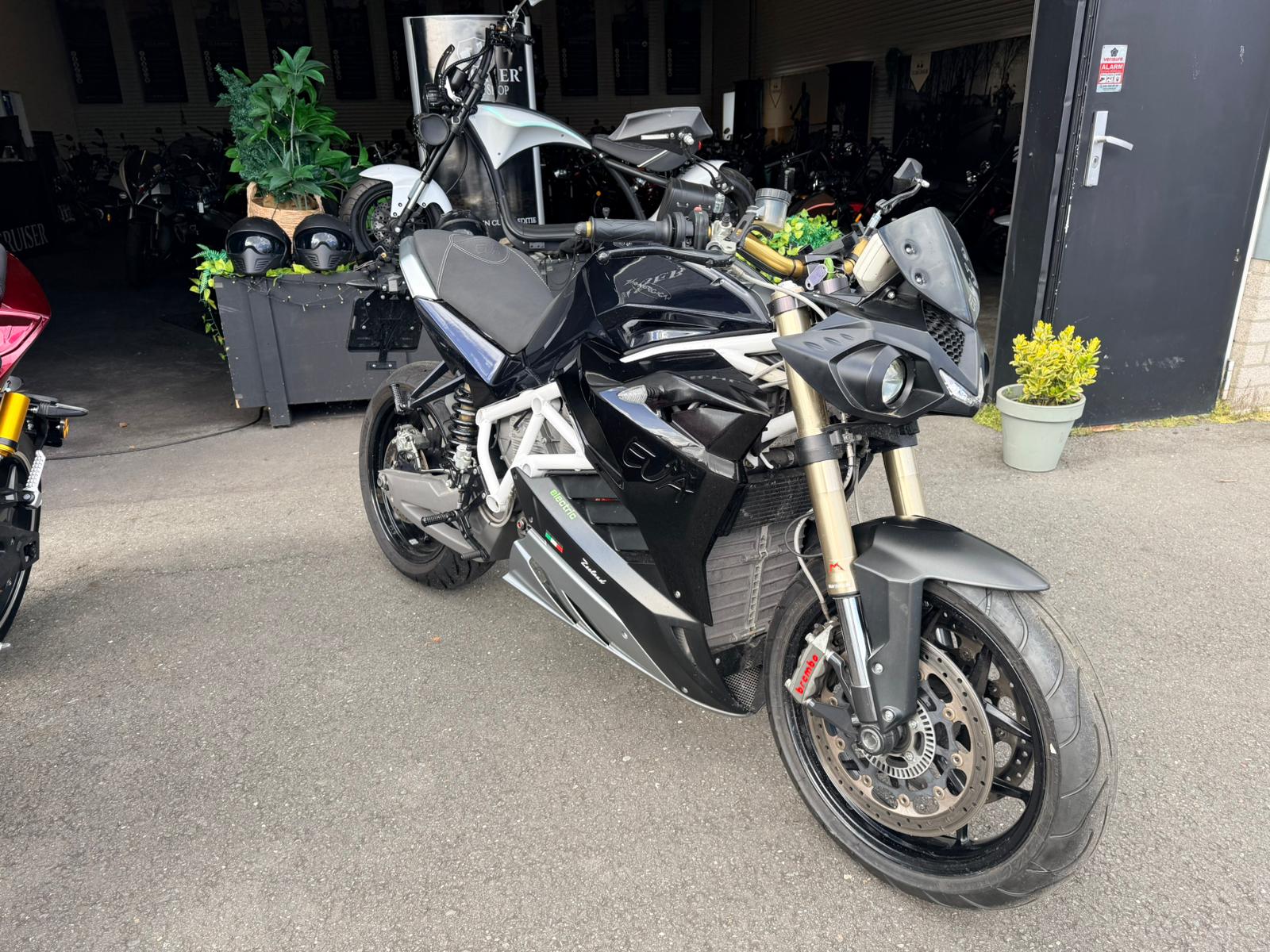 Zwarte Energica EVA R elektrische motorfiets geparkeerd bij showroomingang